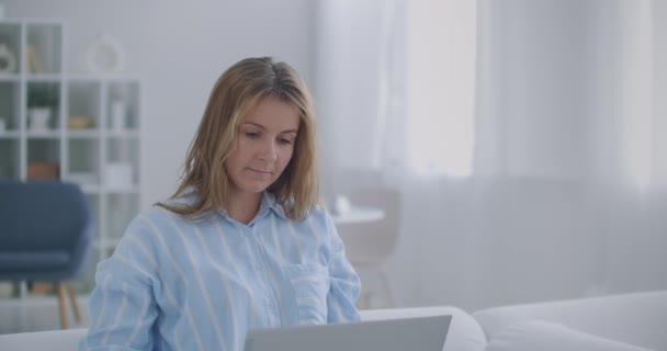 Empresaria enfocada en escribir en el portátil haciendo investigación. Joven profesional usando computadora sentada en el escritorio de la oficina en casa. Trabajador freelancer ocupado trabajando en el dispositivo portátil de tecnología moderna — Vídeo de stock