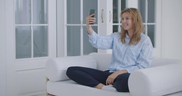 Jovem doente em casa usando Smartphone para falar com vídeo conferência App. Mulher bonita verifica possíveis sintomas com médico profissional, usando chat de vídeo on-line — Vídeo de Stock