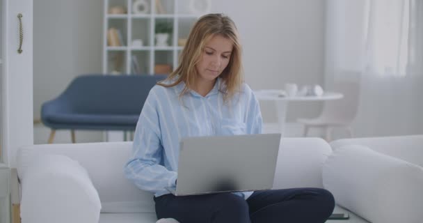 专注的女企业家在笔记本电脑上打字做研究.年轻女性专业使用电脑坐在家里的写字台。忙着操作现代技术笔记本电脑的自由职业者 — 图库视频影像