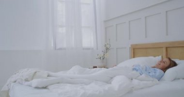 Genç bir kadın sabah otelde uyanıyor ve yudumlayıp gülümsüyor.