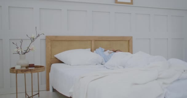 A young woman wakes up in bed in the morning smiling and stretching. Good and cheerful morning. Happy morning — Stock Video