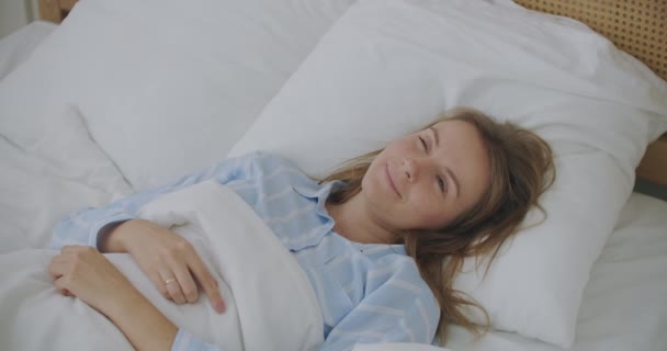 Vacker kvinna vaknar upp och sträcker sig på sängen hemma — Stockvideo
