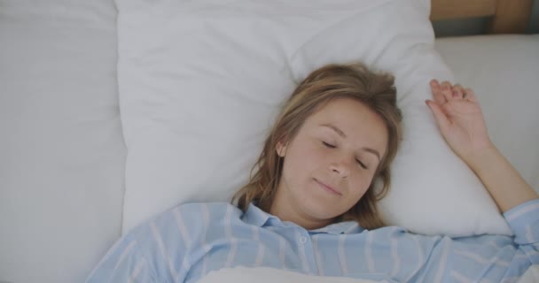 Tutup wajah muda Kaukasia wanita berbaring dan peregangan di tempat tidur setelah bangun pagi-pagi — Stok Video
