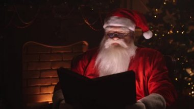 Noel Baba Noel ağacının yanındaki odasında oturuyor ve şöminesinin yanında dinleniyor..