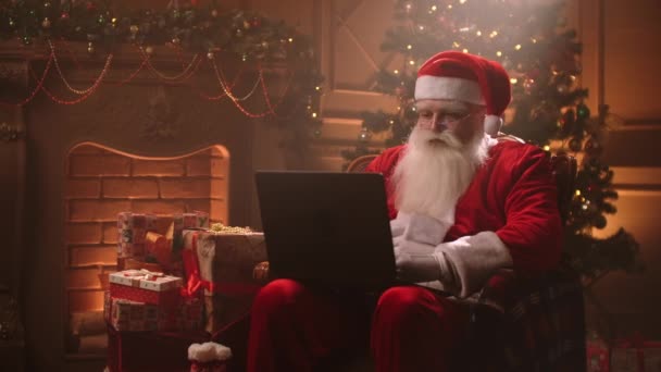 Atmosfera quente Papai Noel na sala de estar usando laptop. — Vídeo de Stock