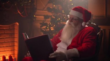 Noel Baba Noel ağacının yanındaki odasında oturuyor ve şöminesinin yanında dinleniyor..