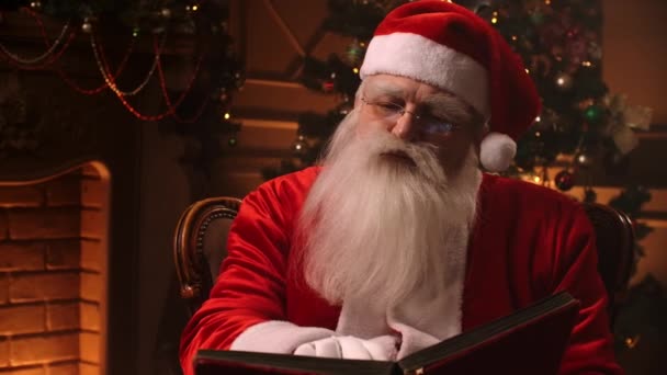 Père Noël assis chez lui dans une chaise confortable et lisant une lettre — Video