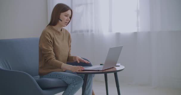 Vrouw communiceert online, met behulp van laptop met internet en koptelefoon met microfoon, online chat, technische ondersteuning — Stockvideo