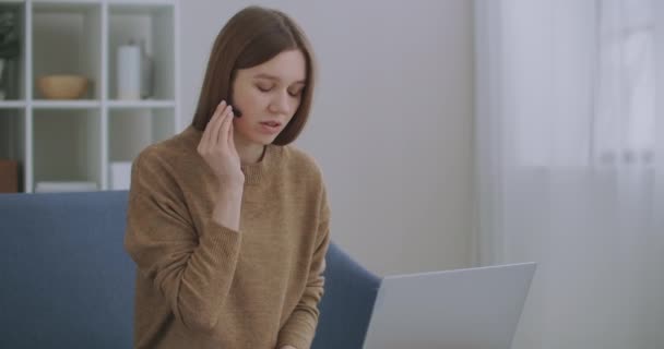 Vrouw communiceert online, met behulp van laptop met internet en koptelefoon met microfoon, online chat, technische ondersteuning — Stockvideo