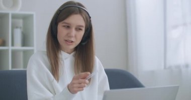 Kadın uzaktan internetle çalışıyor. Mutlu genç iş kadını web kamerasına kulaklık takıyor ve uzaktan video konferans görüşmesi yapıyor. Kadın internet öğretmeni uzaktan sohbet ediyor.