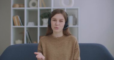 Kafasında kulaklık olan, masada oturan ve kamerayla konuşan internet danışmanı kadının portresi.