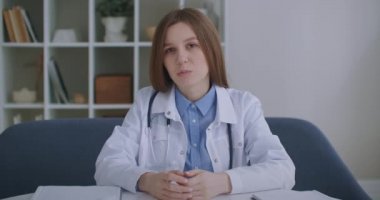 Doktorla çevrimiçi istişare, yaşlı kadın medikal elbiseler giyiyor, dinliyor ve başını sallıyor, kameraya bakıyor.