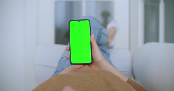 Close-up shot van het groene scherm template smartphone in vrouwelijke handen thuis, meisje is het kijken naar inhoud zonder het aanraken van gadget scherm. Modern concept van technologie en informatie. — Stockvideo