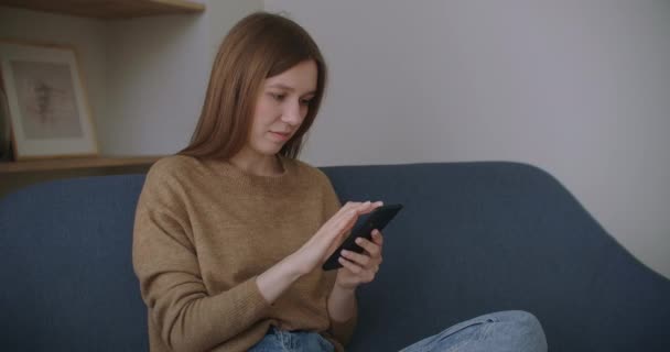Biznesmenka wpisująca wiadomość na komórkę w biurze. Młoda dziewczyna rozmawiająca przez telefon w zwolnionym tempie. Zamknij ręce młodej kobiety za pomocą smartfona na kanapie. — Wideo stockowe