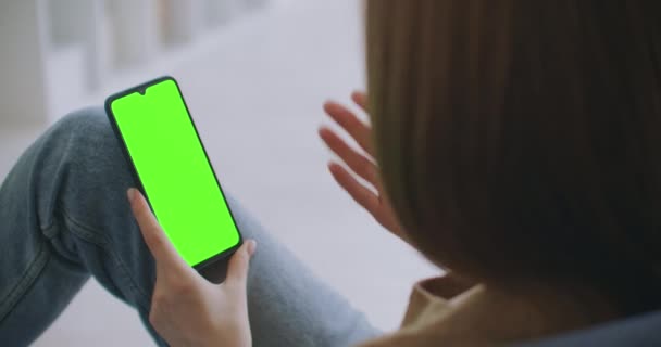 Chica joven está sosteniendo Smartphone con pantalla verde a la hora de la noche. Smartphone en mano, imágenes estáticas con pequeños movimientos de mano. indicadores en la pantalla para rastrear el movimiento — Vídeos de Stock