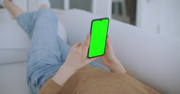 Close-up shot van het groene scherm template smartphone in vrouwelijke handen thuis, meisje is het kijken naar inhoud zonder het aanraken van gadget scherm. Modern concept van technologie en informatie. — Stockvideo