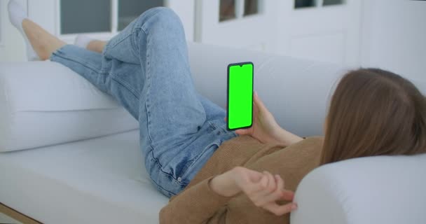 Giovane ragazza è in possesso di smartphone con schermo verde al momento della sera. Smartphone in mano, riprese statiche con piccoli movimenti di mano. indicatori sullo schermo per monitorare il movimento — Video Stock