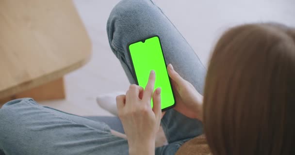 Žena doma ležící na gauči pomocí Smartphone se zelenou Mock-up Screen, Dělat Swiping, Scrolling Gestures. Chlápek používající mobilní telefon, prohlížení internetových sociálních sítí. Snímek z pohledu kamery — Stock video