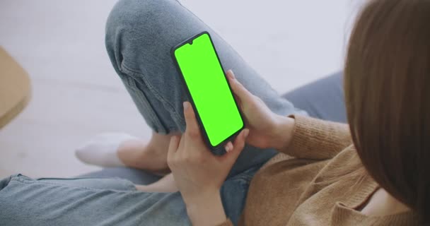 Green Mock-up Screen ile Smartphone kullanarak Kanepede uzanan, Swiping, Scrolling Jestleri yapan kadın. Adam cep telefonu kullanıyor, internet sosyal ağları tarıyor. Görüntü Kamerası Görüntüsü — Stok video