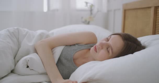 Mujer joven acostada en la cama sufre de ruido generado por el sitio de construcción fuera de la ventana. Mujer cubriéndose las orejas con almohada. — Vídeo de stock