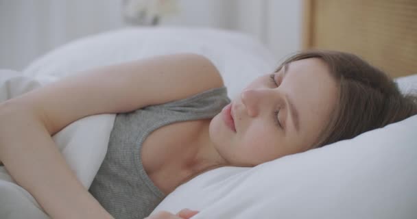 La mujer se despierta levanta estira las manos en la cama se siente saludable — Vídeo de stock