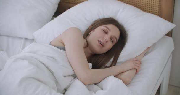 La mujer se despierta levanta estira las manos en la cama se siente saludable — Vídeo de stock