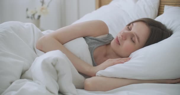 Smilende kvinde vågner. Teenagekvinde vågner op derhjemme. Ung pige strækker sig efter vågen start af en ny dag med energi og vitalitet på sengen nær vinduet i soveværelset om morgenen, bakvisning. – Stock-video