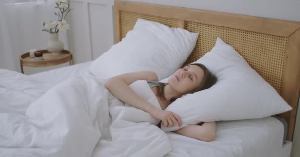 Smiling Woman Waking Up. Teen hispanic woman wakes up at home. Young girl stretching after awake starting a new day with energy and vitality on bed near window in bedroom at morning, back view. — Stock Video