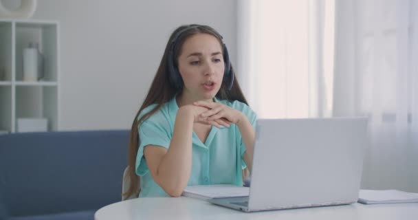 Operatrice nei call center. Giovane donna d'affari con le cuffie che comunica tramite videochiamata. donna d'affari che parla guardando computer portatile, conferenza online distanza ufficio chat — Video Stock