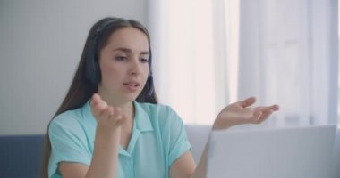Çağrı Merkezi 'ndeki kadın operatör. Kulaklık takan genç bir iş kadını video görüşmesiyle iletişim kuruyor. Dizüstü bilgisayara bakan iş kadını, online konferans uzaklık ofis sohbeti