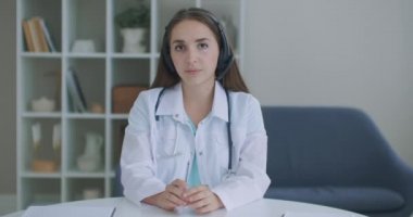 Kameraya bakıp dinleyen kadın doktor kameraya bakar ve hastayı dinler. Video konferans dinleyicisi. Bir doktorun portresi.