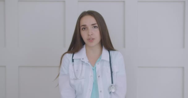 Smiling young female doctor wear white uniform stethoscope consulting online patient via video call looking at camera speaking cam do distance video chat, telemedicine and e-health concept, webcam — Stock Video
