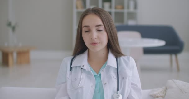 En regardant la caméra, la femme qui écoute le médecin regarde la caméra et écoute le patient. Un auditeur de vidéoconférence. Portrait d'un médecin — Video