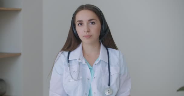 Looking at the camera listening woman doctor looks at the camera and listens to the patient. A video conference listener. Portrait of a doctor — Stock Video