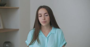 Kadın kameraya bakarken dinliyor ve onaylayarak başını sallıyor. Video arama diyaloğuna katılımcı. Video konferans dinleyicisi evde oturuyor