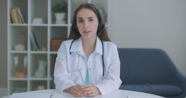 Kameraya bakıp dinleyen kadın doktor kameraya bakar ve hastayı dinler. Video konferans dinleyicisi. Bir doktorun portresi.