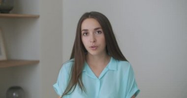 Baş fotoğrafçı kadın kanepeye otur ve kameraya bak. Arkadaşını selamla. Kısa kıvırcık saçlı genç bir kadın video konferans konseptiyle keyifli sohbetler ediyor.