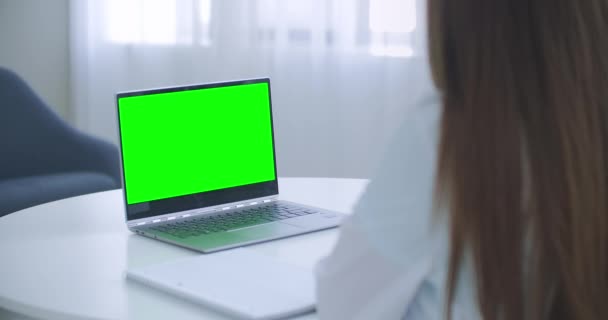 女性医師はオンラインで相談しています,テーブルの上に緑の画面を持つノートパソコン,クロマキーコンセプト — ストック動画