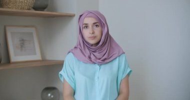 Tesettürlü bir kadın kameraya bakar ve sessizce başını sallar ve dinler. Video bağlantısı üzerinden konuşma. Video konferansı doktorların tavsiyelerini dinleyin.. 