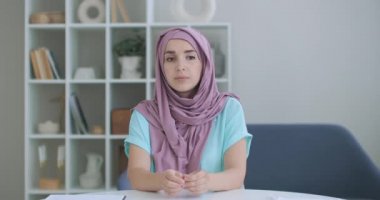 Tesettürlü bir kadın kameraya bakar ve sessizce başını sallar ve dinler. Video bağlantısı üzerinden konuşma. Video konferansı doktorların tavsiyelerini dinleyin.. 