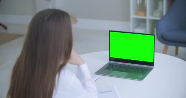 Trabajadora médica una mujer con un abrigo blanco utiliza una tableta en la oficina en el escritorio, cromakey en la pantalla de la tableta, una vista sobre su hombro. médico hablando con el ordenador portátil con pantalla verde. — Vídeos de Stock