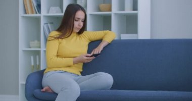 Akıllı telefon kullanan bir kadın. Güzel kız modern akıllı telefon kullanıyor ekrana dokunuyor ve evde gülümsüyor.