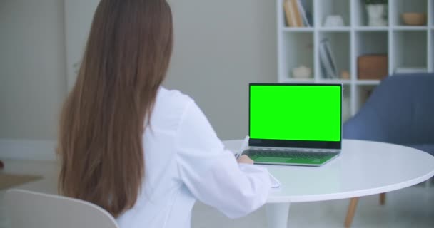 Γυναίκα γιατρός είναι σύμβουλος σε απευθείας σύνδεση, φορητό υπολογιστή με πράσινη οθόνη στο τραπέζι, χρωματική έννοια κλειδί — Αρχείο Βίντεο