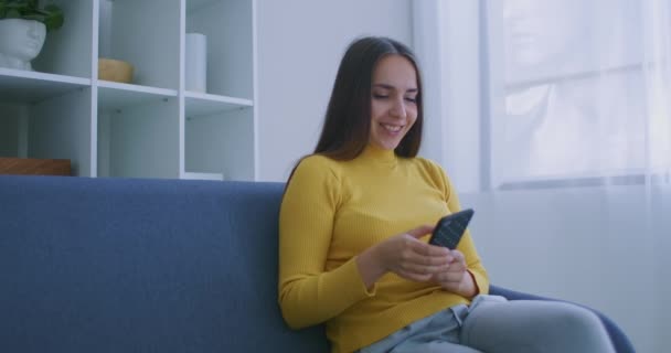 Žena používající smartphone. Hezká dívka pomocí moderního smartphone dotykové obrazovky a usmívá se doma — Stock video