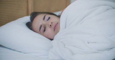 Pijamalı çekici esmer kadın uykusuz ve uykusuz bir şekilde yatakta yatıyor..