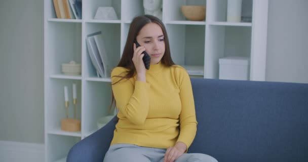 Felice donna matura con parlare su smartphone mentre seduto in soggiorno con interni moderni. Concetto di tecnologia e relax. — Video Stock