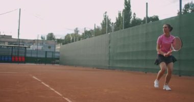  Sahada tenis oynayan beyaz bir kadın ağır çekimde topu geri getiriyor.