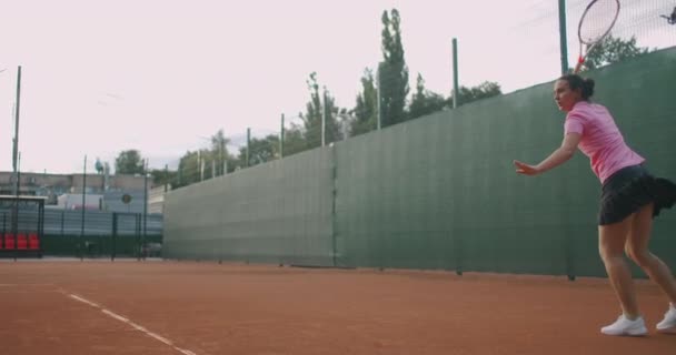 Jovem tenista feminina concentrando-se e focando em seu jogo de antemão. Profissional feminino equipado batendo duro a bola de tênis com raquete de tênis. — Vídeo de Stock