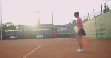 Kadın tenisçi profesyonel stadyumda maç sırasında iş başında. O markasız spor giysiler giyiyor. Stadyum