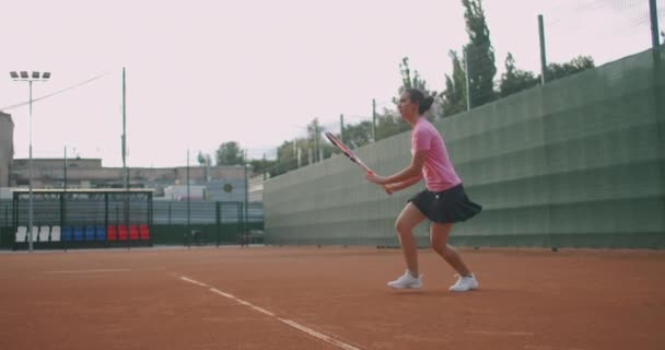 Женщина теннисистка в действии во время игры на профессиональном стадионе. На ней неклейменная спортивная одежда. Стадион — стоковое видео
